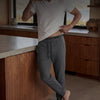Person wearing a white t-shirt and gray pants in a kitchen.